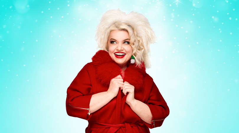 blond women in Christmas themed red robe, smiling with red lipstick, on light blue background