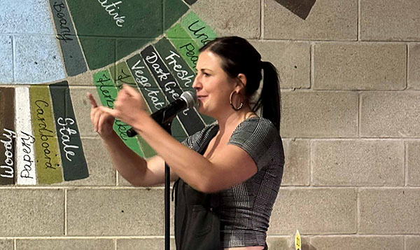 Women gesturing with her hands while standing in front of a microphone performing at a Poetry Slam event