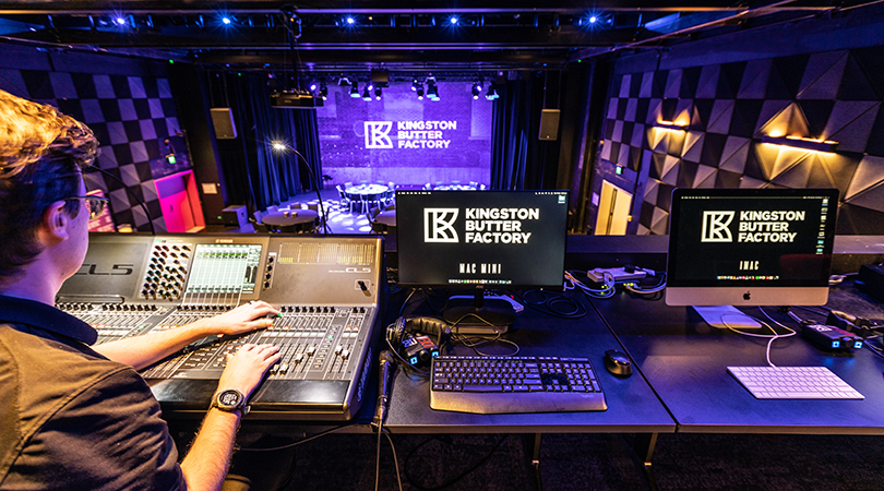 Trainee working with audio equipment at the back of the stage.